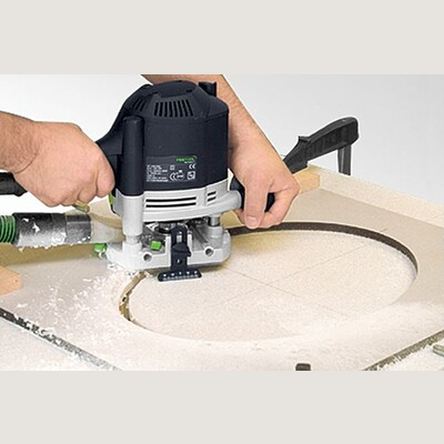 Hands guiding a router cutting a clean circular groove in a light-colored wood panel for home improvement projects