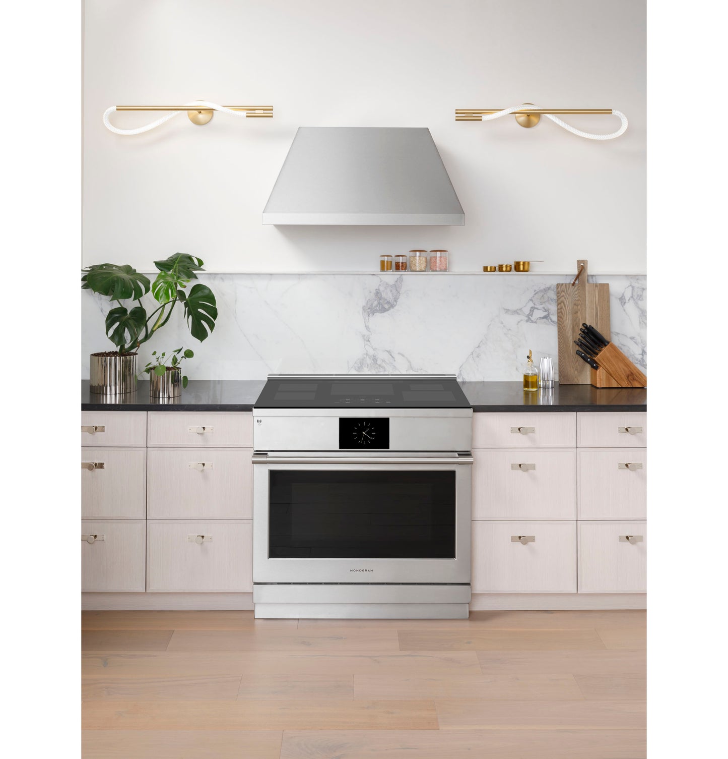 Stainless steel induction range with black glass cooktop and digital display in contemporary kitchen setting