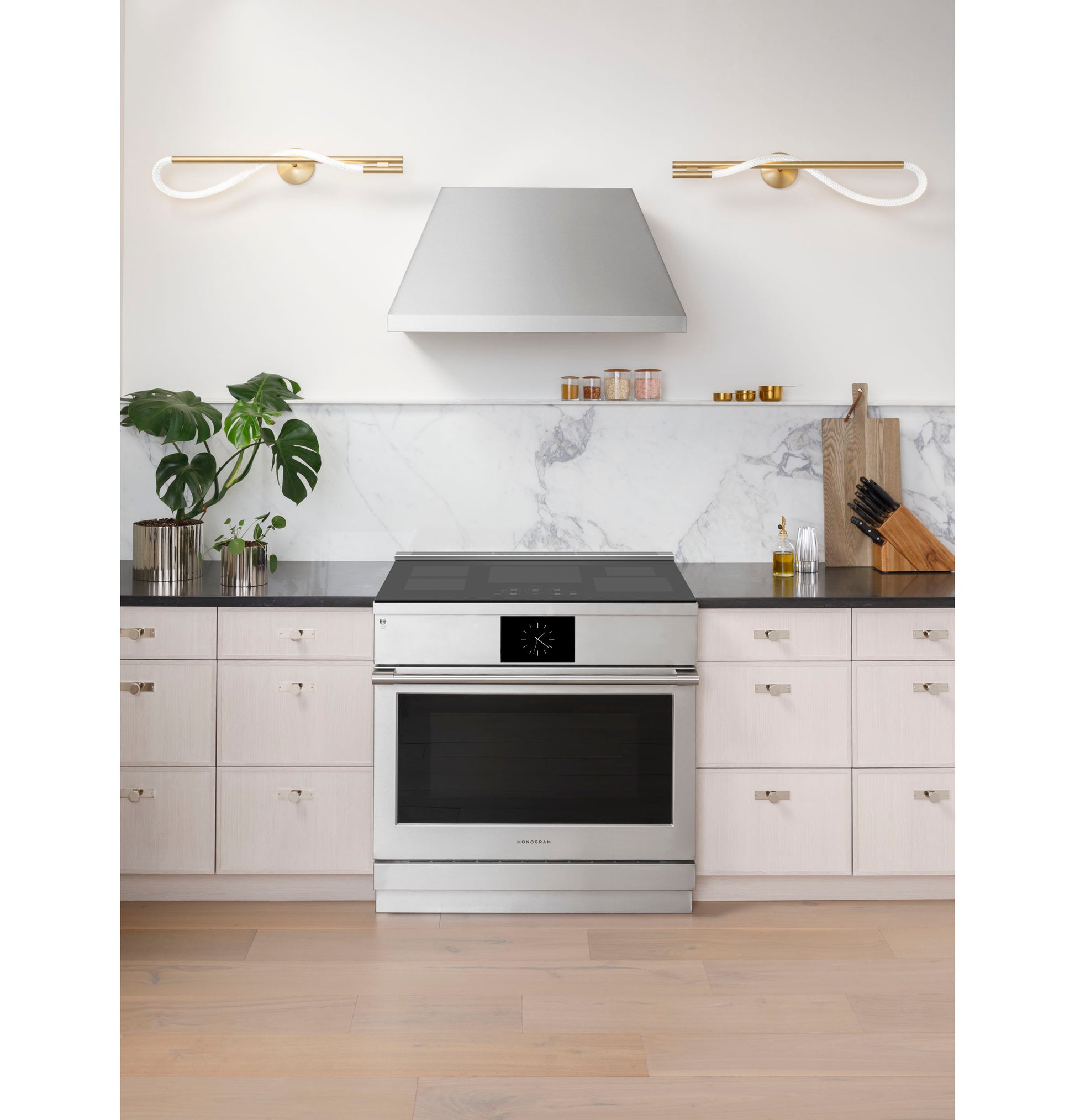 Stainless steel induction range with black glass cooktop and digital display in contemporary kitchen setting