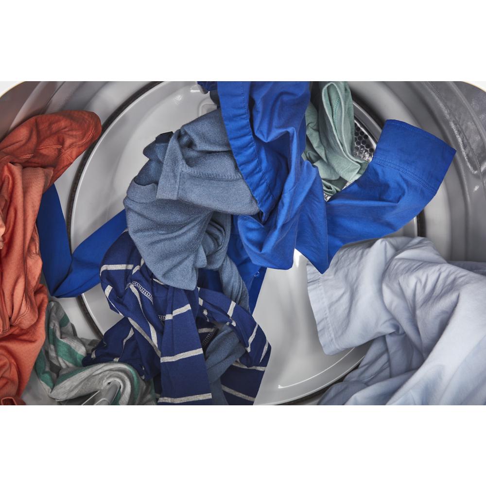 Various colorful clothes tumbling inside an electric dryer drum in a residential appliance setting