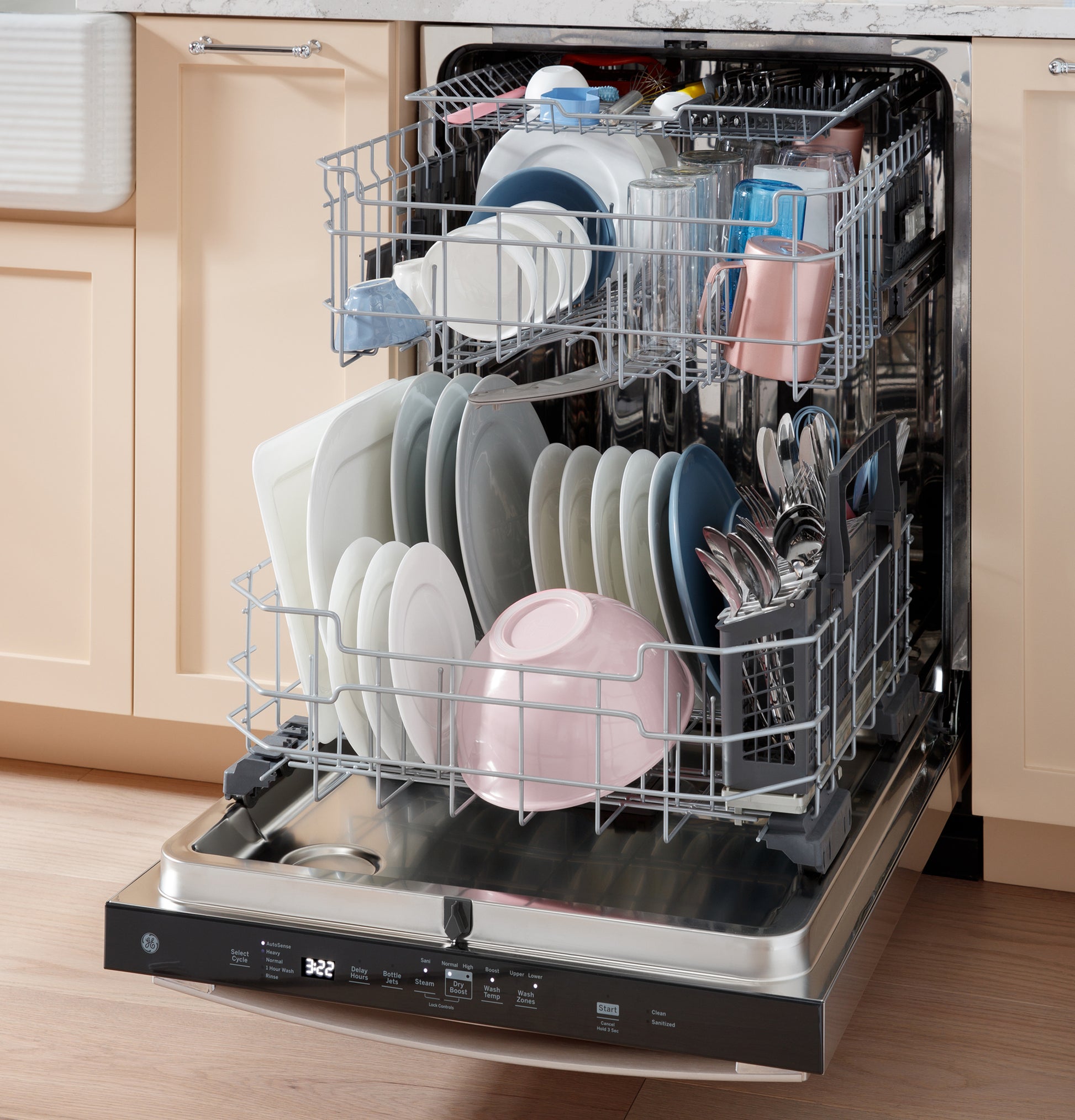 Open GE dishwasher with stainless steel interior loaded with clean dishes and utensils in kitchen setting