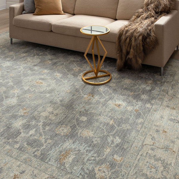 Soft textured dark gray area rug with muted floral and vine design in a cozy living room setting