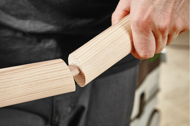 Close-up of a hand joining two wooden pieces using a beech wood domino tenon for woodworking tool accessories.