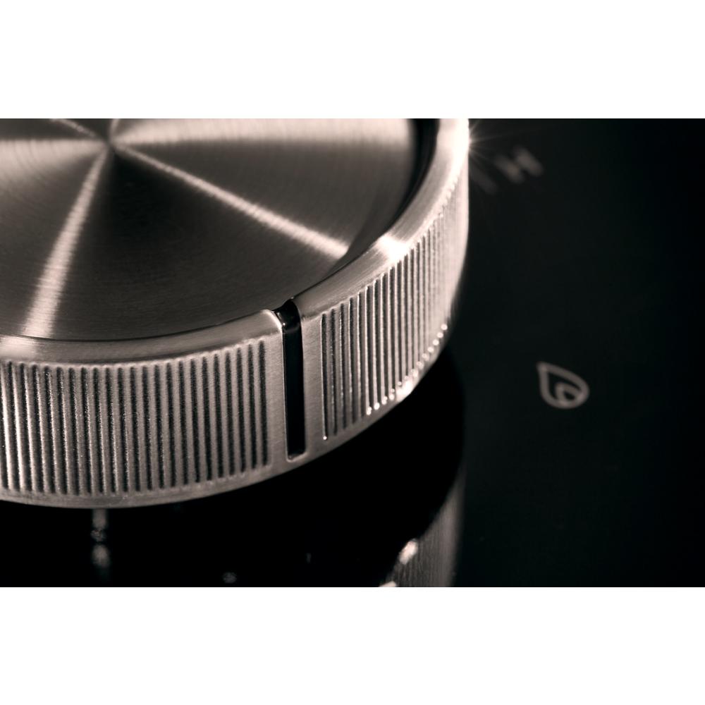 Close-up of a textured silver control knob on a black glass surface for a modern cooktop in kitchenware collection