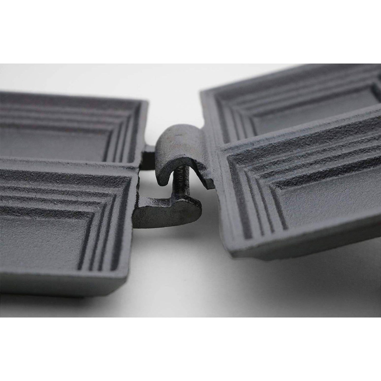 Close-up of hinge mechanism on black cast iron double sandwich cooker for cooking over campfires and outdoor use
