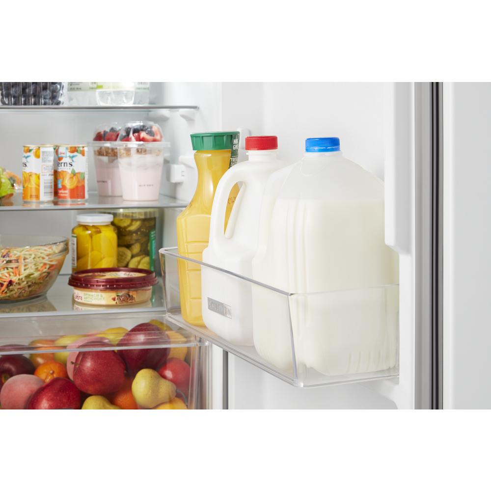 Inside view of refrigerator door shelf holding gallon jugs of milk and orange juice in kitchen appliances category