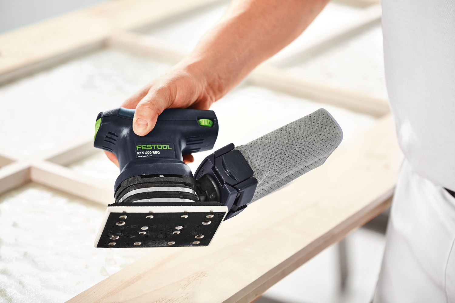 Handheld Festool orbital finish sander smoothing wood surface for precision home improvement tasks