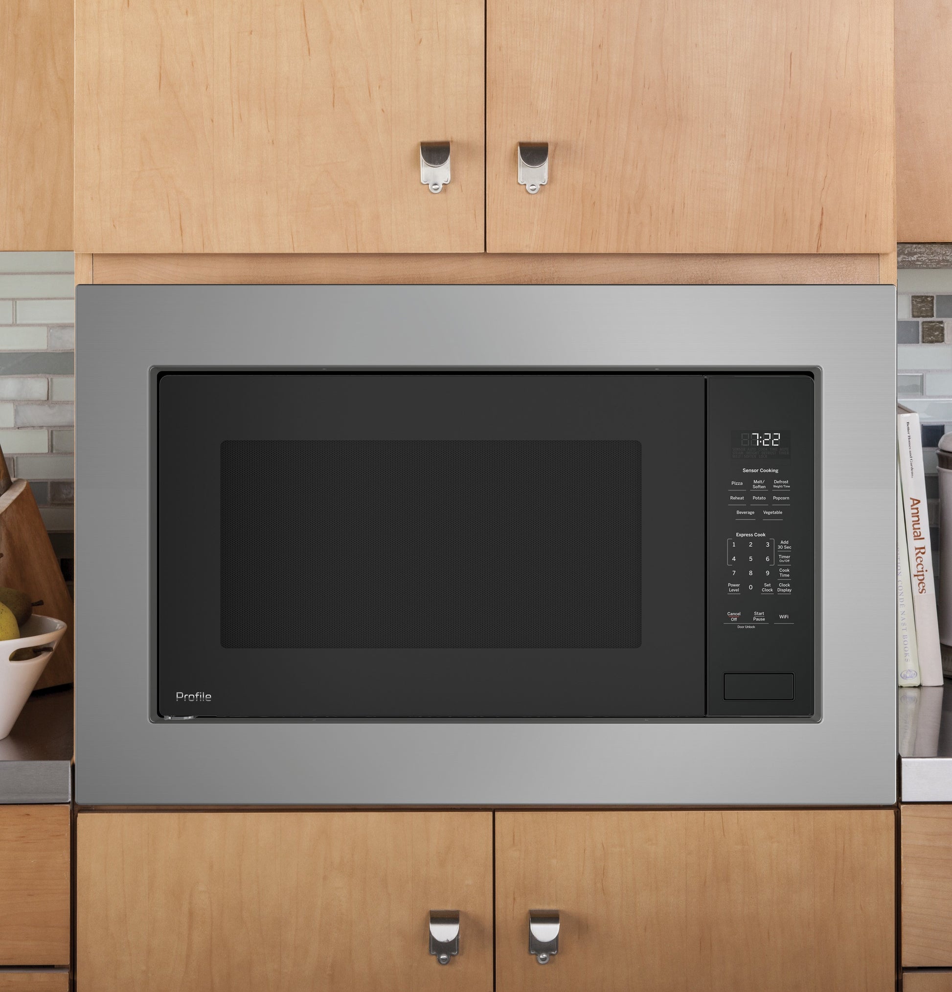 Built-in stainless steel microwave oven with sensor controls and digital display integrated into wooden kitchen cabinetry