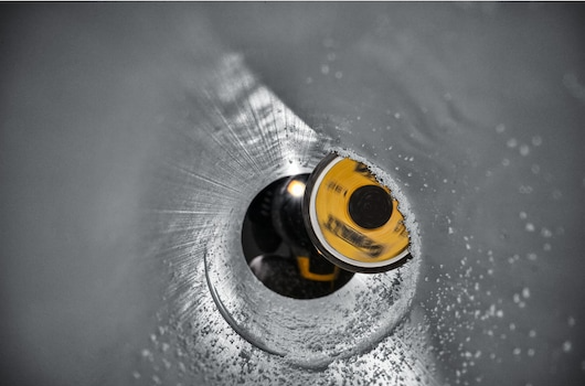 Close-up view through PVC pipe showing yellow cutting blade of inside pipe cutter tool in home improvement use
