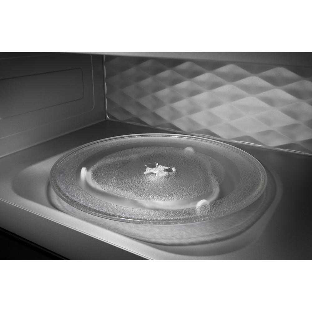 Interior view of built-in microwave with glass turntable and patterned stainless steel back wall panel