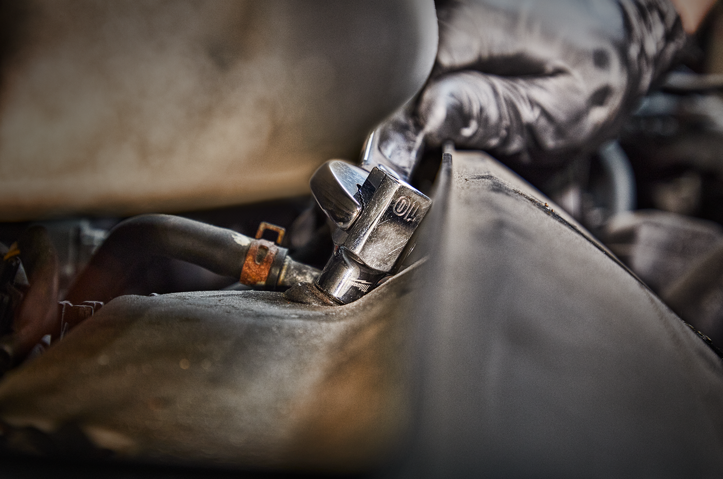 Close-up of a chrome 6-point socket attached to a ratchet wrench in a mechanical or automotive repair setting