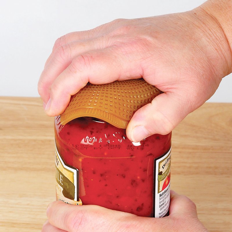 Hand using a textured jar opener grip to twist off a lid from a glass jar in kitchenware collection
