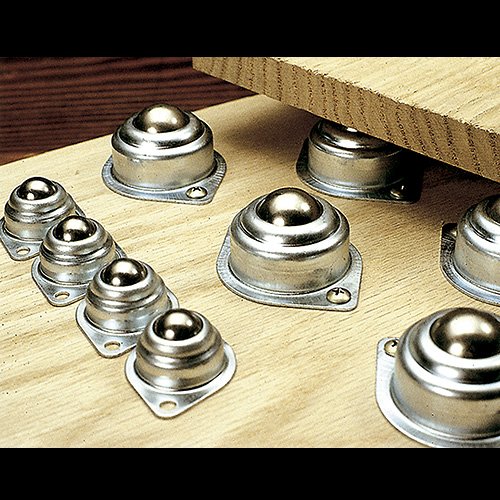 Set of large single-ball rollers mounted on wood surface for smooth movement of heavy boards in woodworking tasks