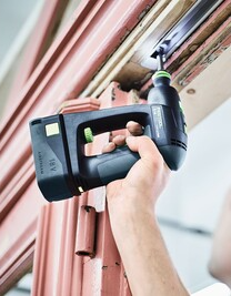Person using a cordless drill on a metal door frame, part of electric power tools for woodworking and home improvement