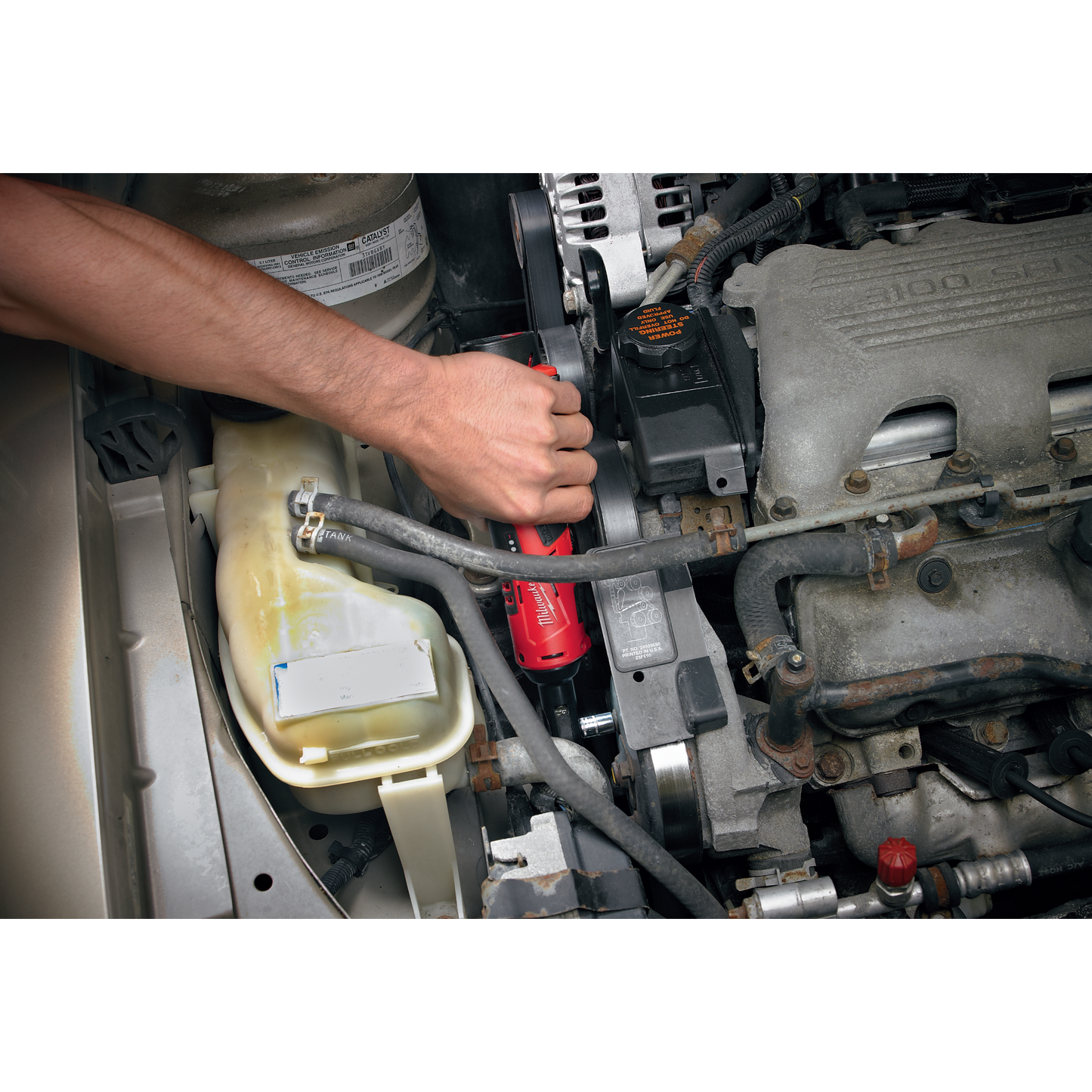 Hand using compact cordless ratchet wrench on engine belt in vehicle for tools and home improvement task