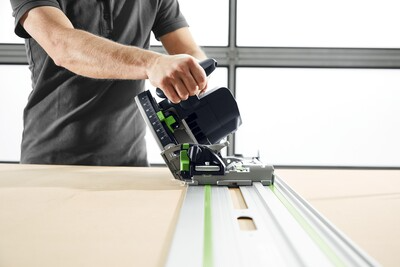 Person guiding Festool plunge cut track saw on guide rail for accurate cuts in power tools and home improvement projects