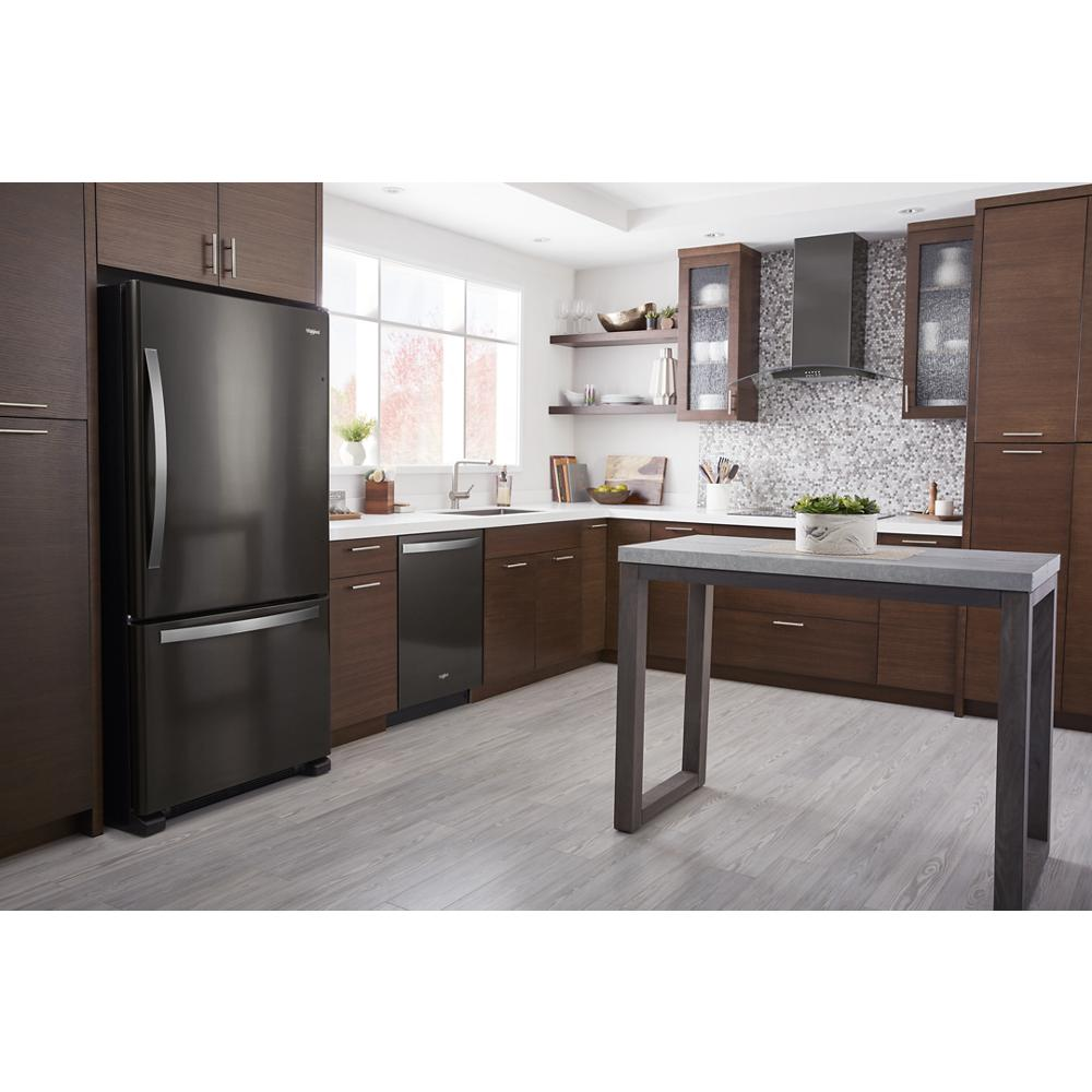 Modern kitchen with dark bottom-freezer refrigerator, wood cabinets, gray flooring, and minimalist island table near window