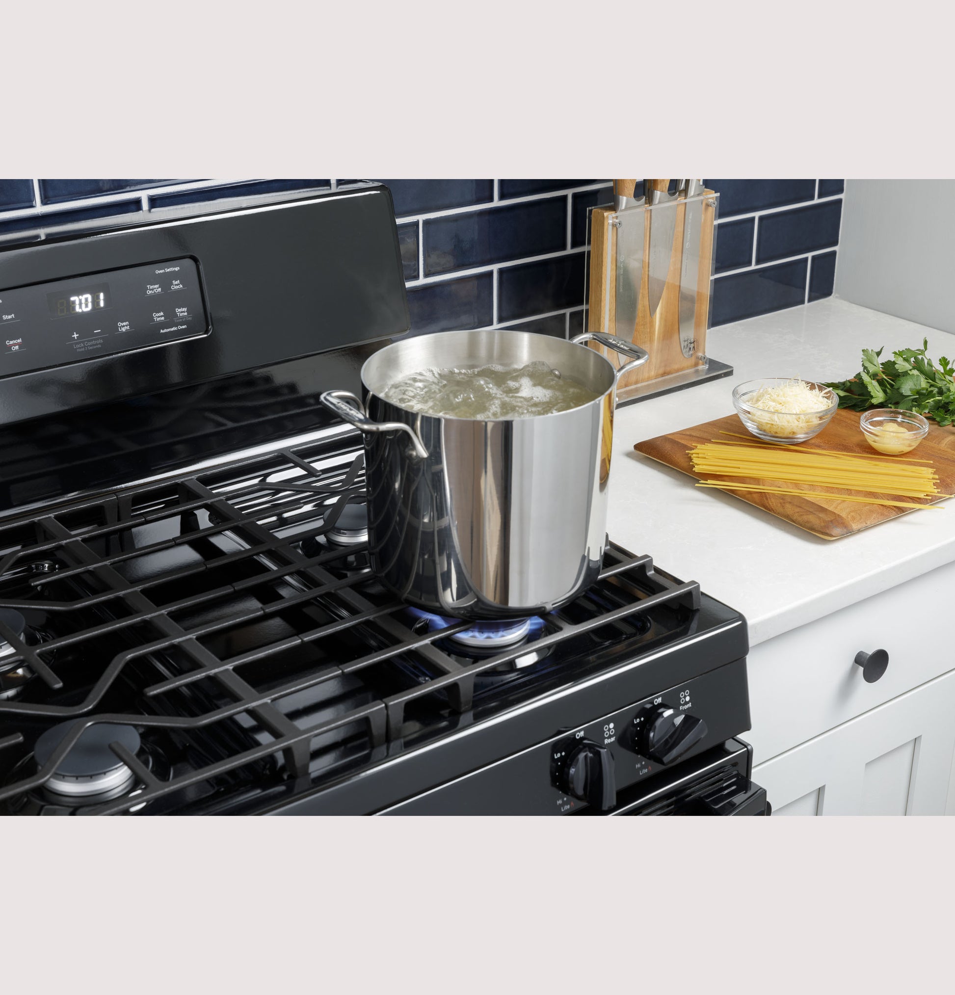 Black gas range with digital controls heating a stainless steel pot boiling water in kitchen appliances collection