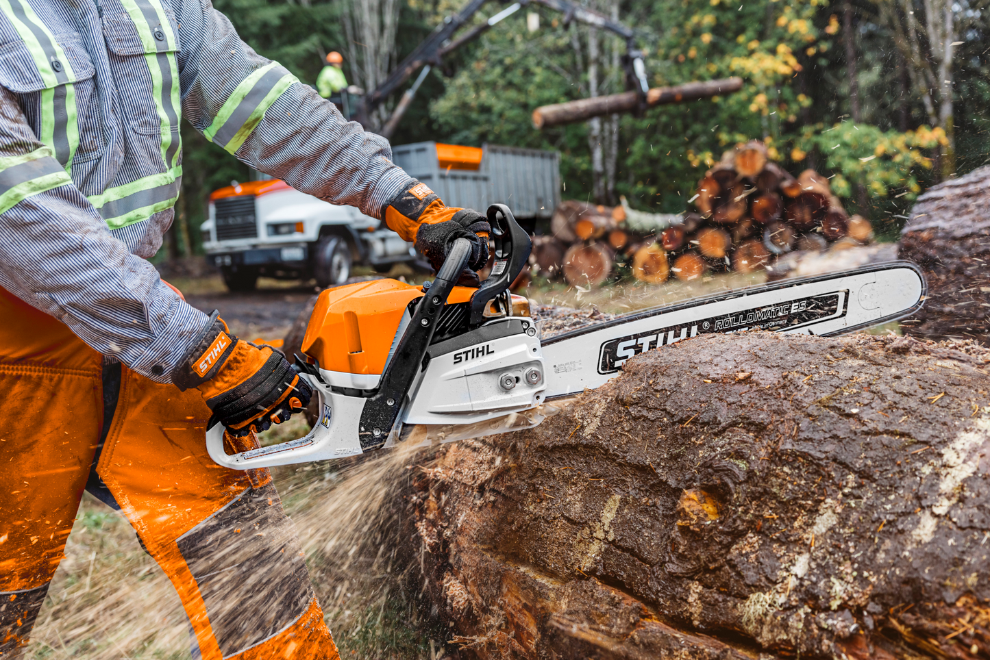 Orange and white chainsaw cutting large log outdoors with safety gear for tools and home improvement use