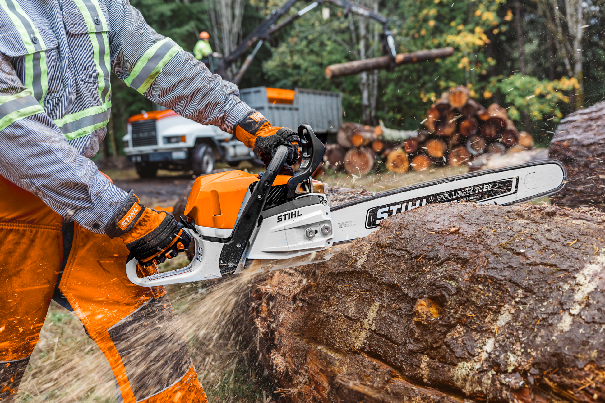 Orange and white chainsaw cutting large log outdoors with safety gear for tools and home improvement use