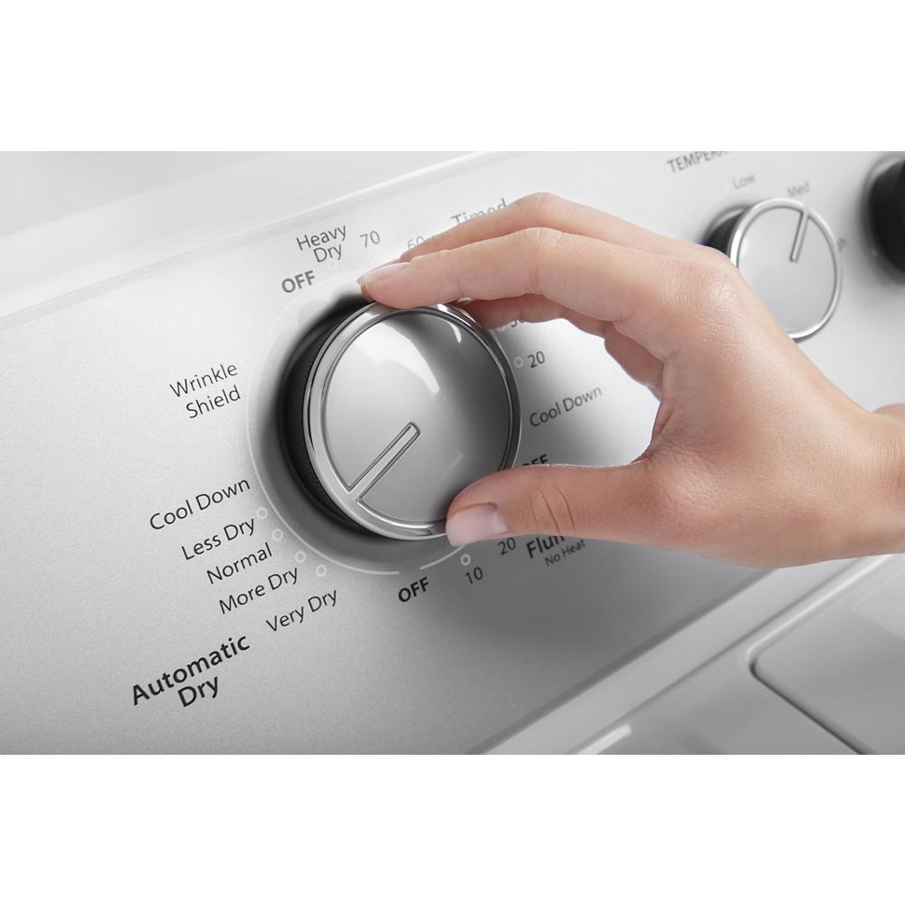 Hand adjusting the cycle selection knob on silver control panel of top load gas dryer in laundry room setting