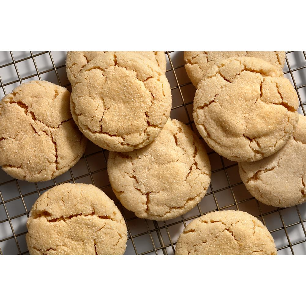 Close-up of sugar cookies with cracked tops cooling on a wire rack in kitchenware setting