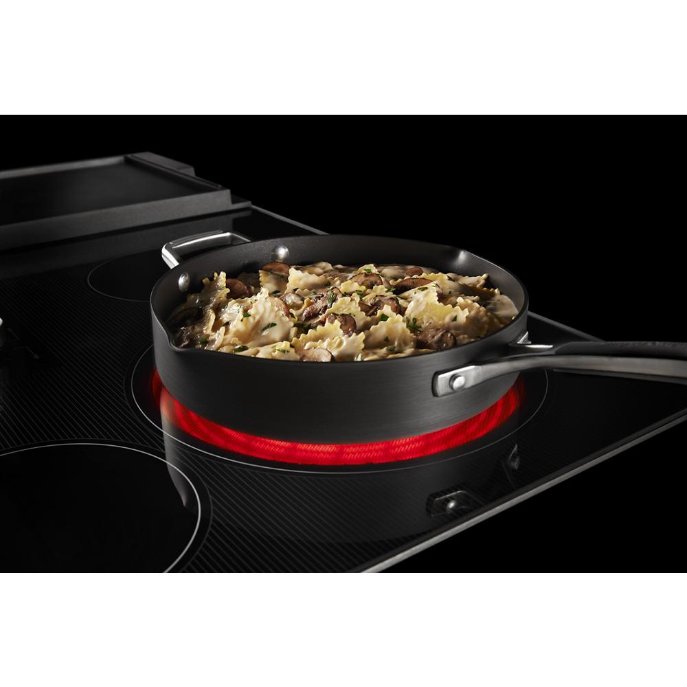 Black electric cooktop heating a skillet with pasta dish, part of electric cooktops and kitchenware collections