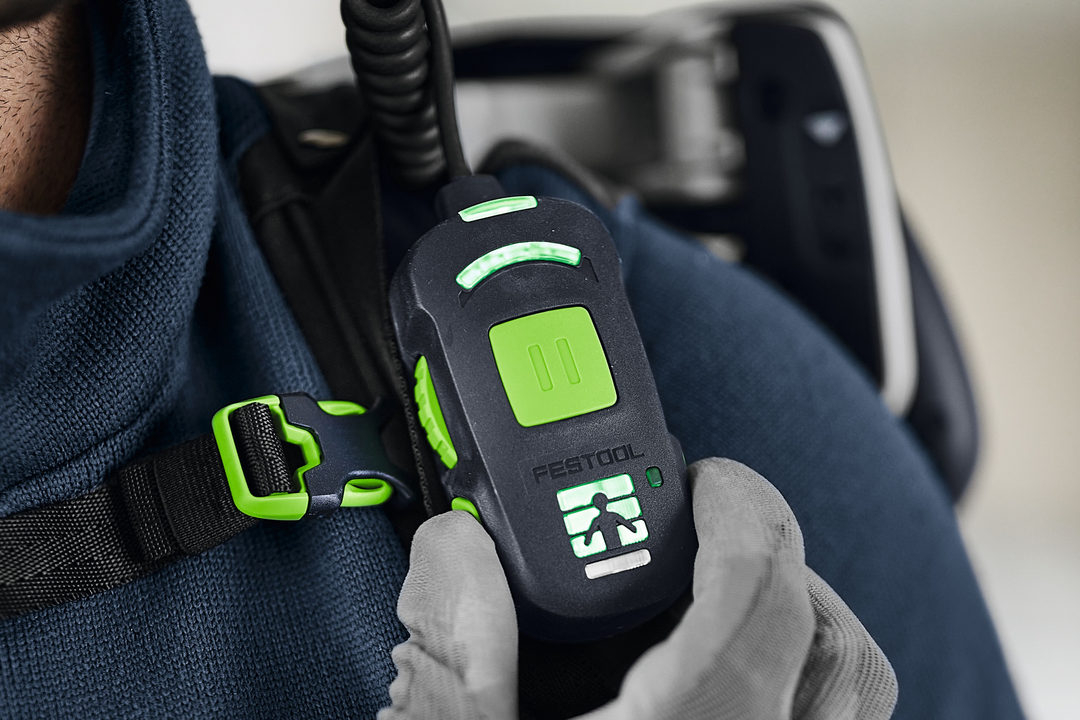 Close-up of hand adjusting green control device on black and green ergonomic exoskeleton for power tool support