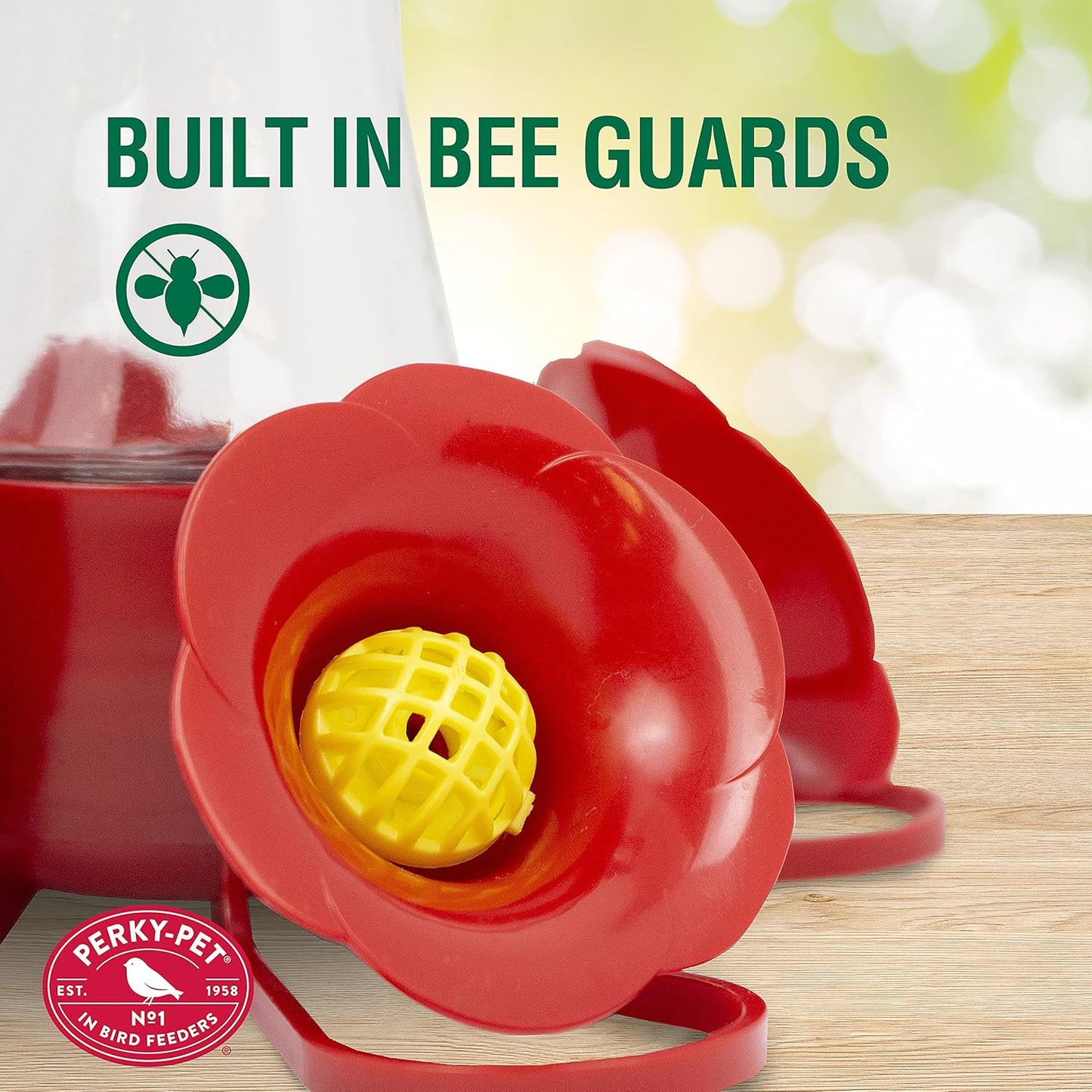 Close-up of red flower-shaped feeder ports with yellow built-in bee guards on a wooden surface outdoors