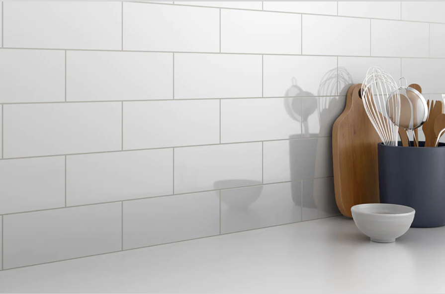 Glossy white ceramic subway tiles in kitchen backsplash with wooden cutting boards and utensil holder under $50 collection