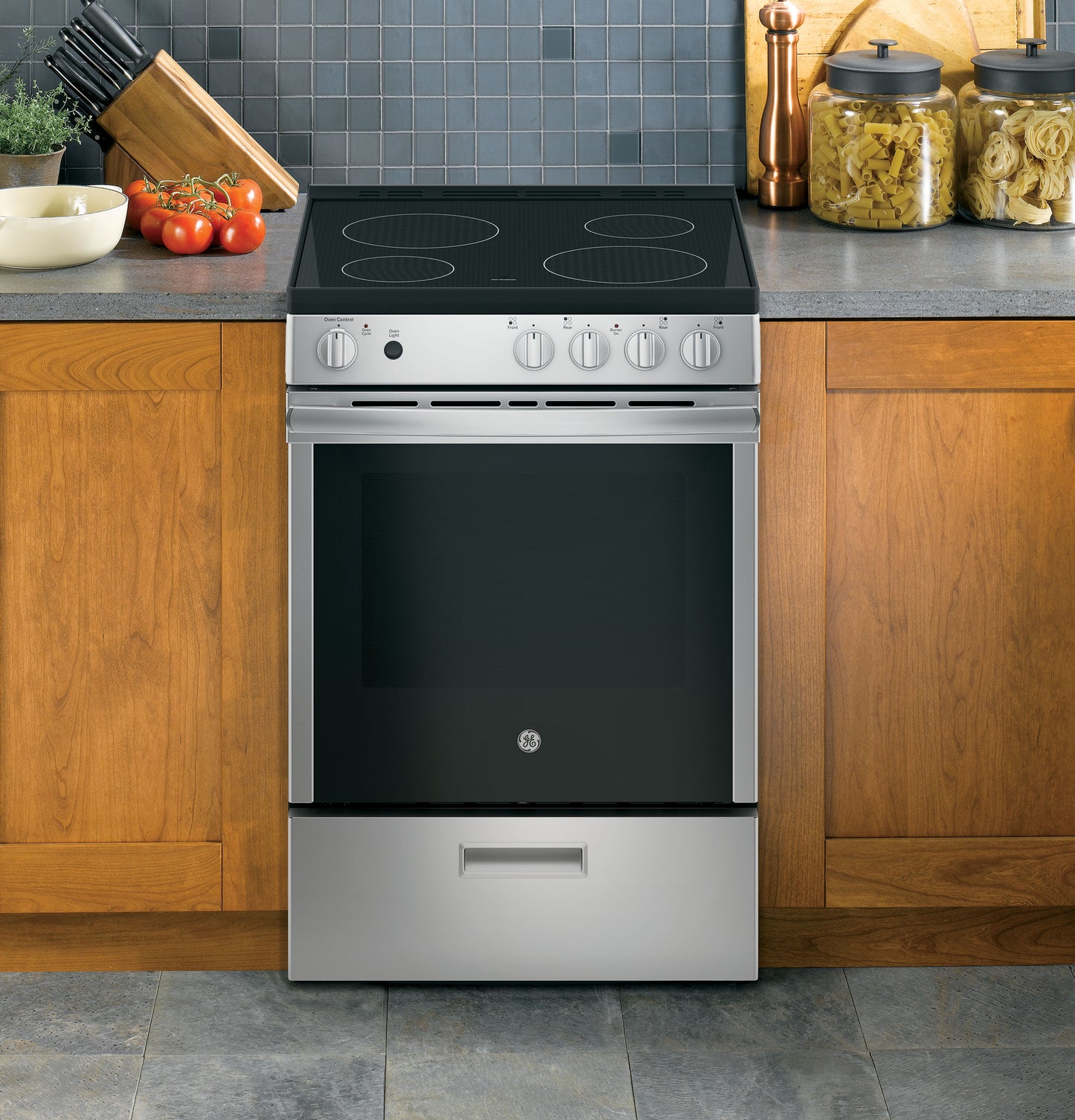 Stainless steel front control range with smooth black induction cooktop in kitchen with wood cabinets and tiled backsplash