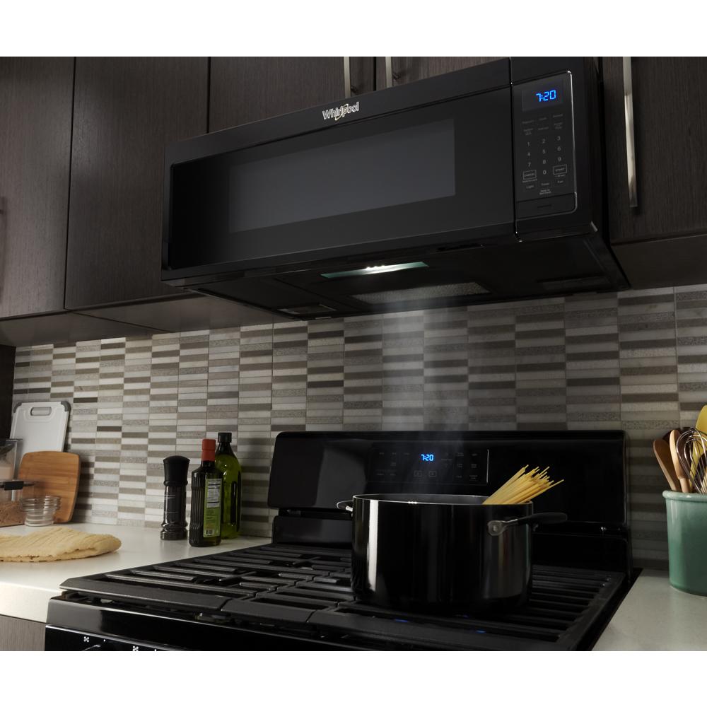 Black low-profile microwave with digital controls and vent fan operating above stove cooking pot in modern kitchen
