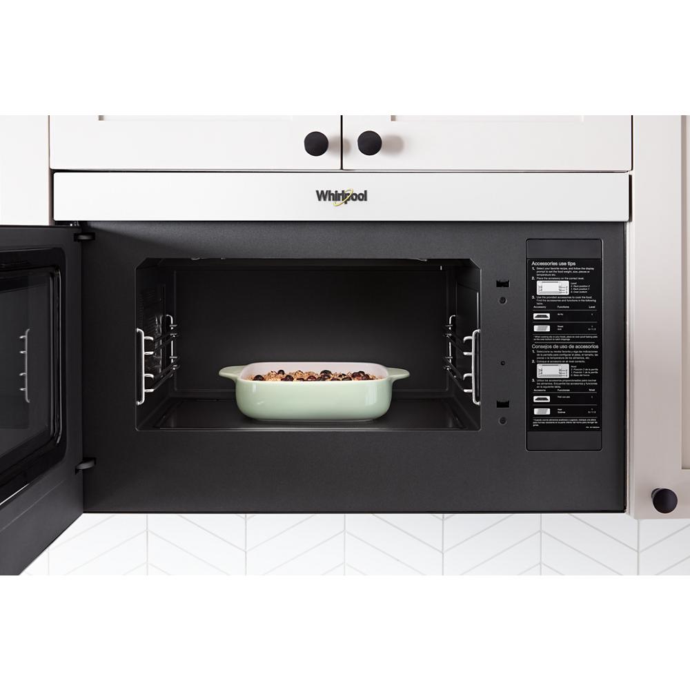Open Whirlpool air fry over-the-range microwave with ceramic dish inside in modern kitchen setting