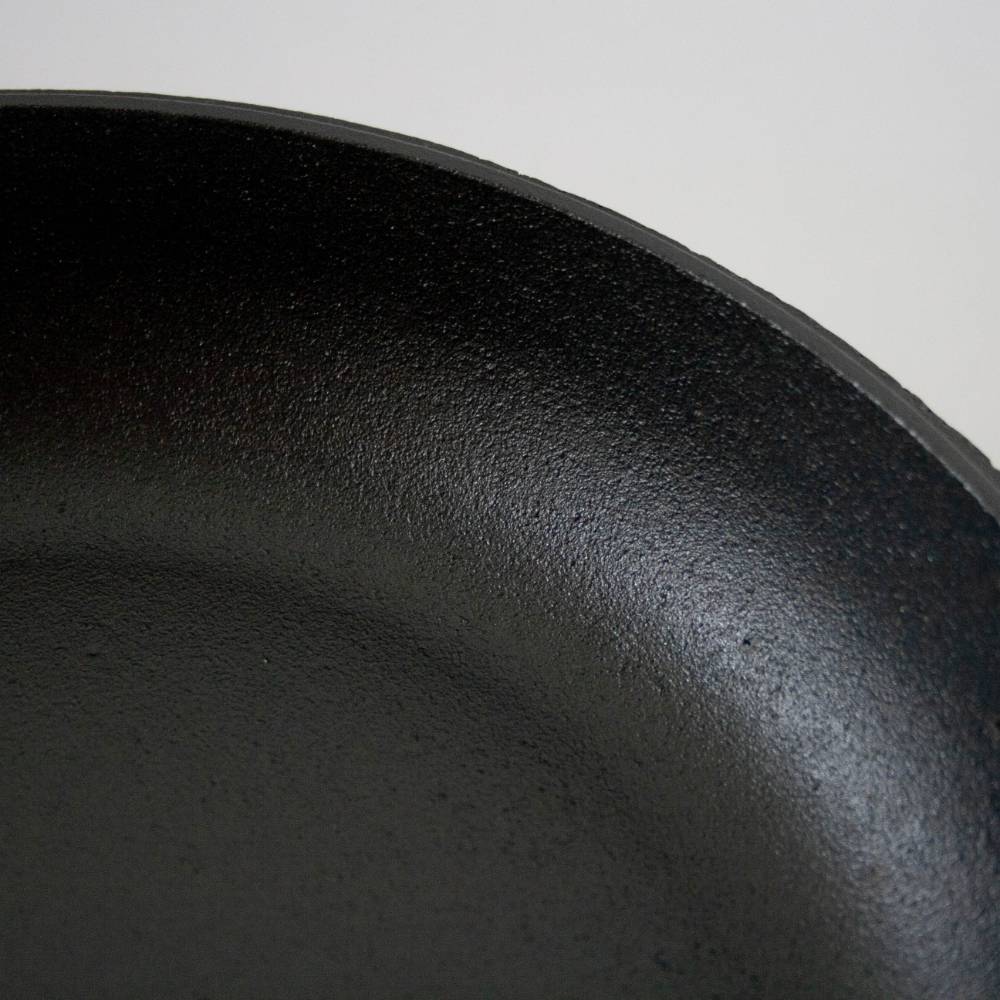 Close-up of smooth black cast iron skillet surface highlighting its seasoned texture in kitchenware collections under $100
