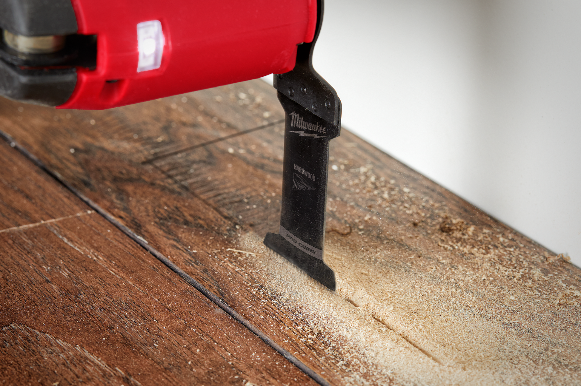Milwaukee OPEN-LOK multi-tool blade cutting hardwood with sawdust on wood surface in woodworking tool accessories