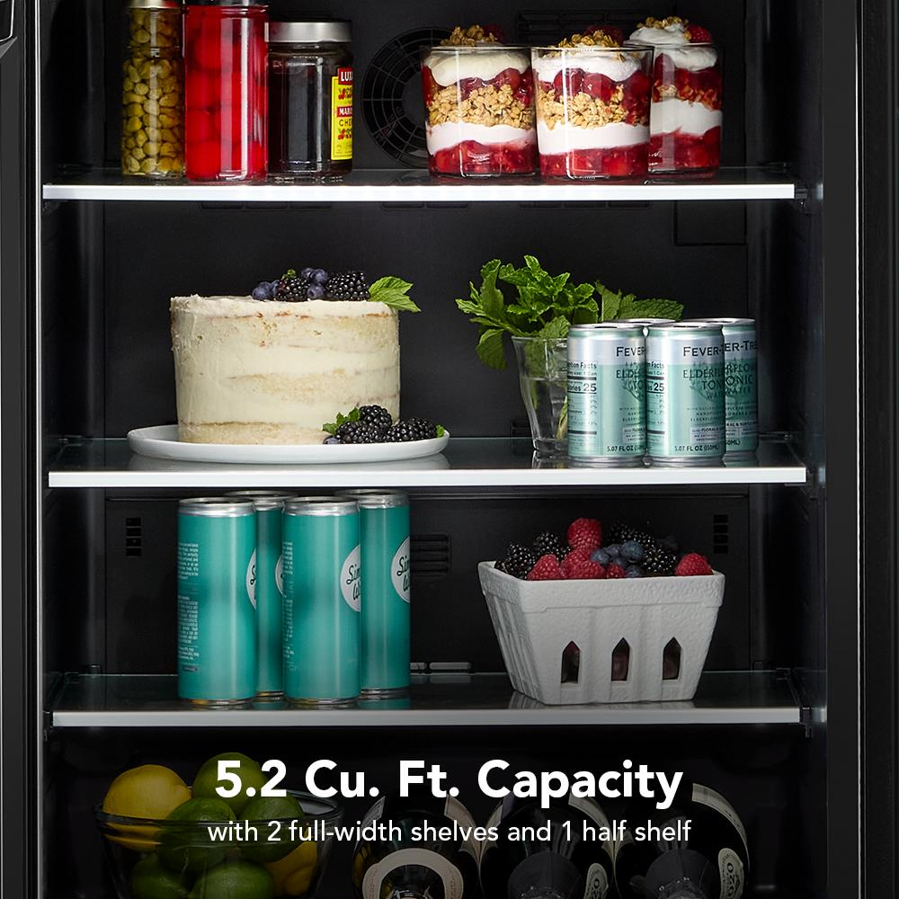 Open view of undercounter refrigerator with metallic-accented glass shelves holding desserts, beverages, and fresh fruit