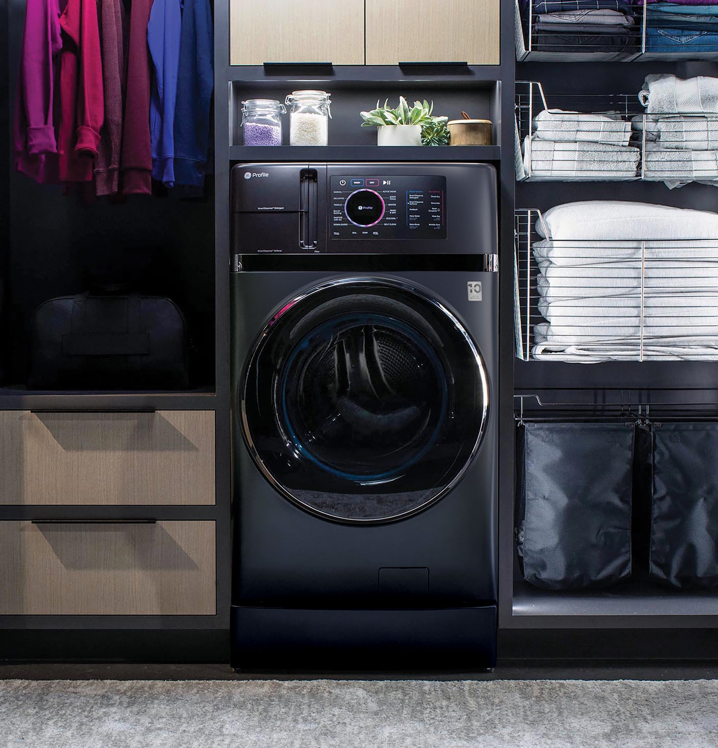Black front-load washer/dryer combo with digital touch controls integrated into modern laundry room cabinetry and shelving.
