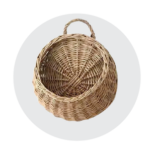 Round handwoven wicker basket with a single loop handle, shown against a neutral light circular background.
