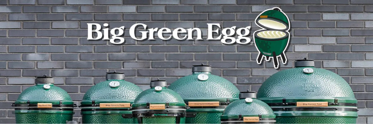 Line of green ceramic grills of varying sizes with domed lids, positioned against a gray brick wall beneath a white stylized logo and text reading Big Green Egg.