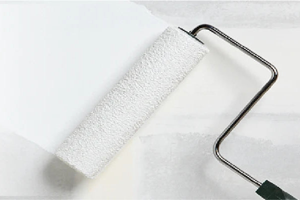 Paint roller with white paint partially covering a light gray surface, illustrating a home improvement painting task.