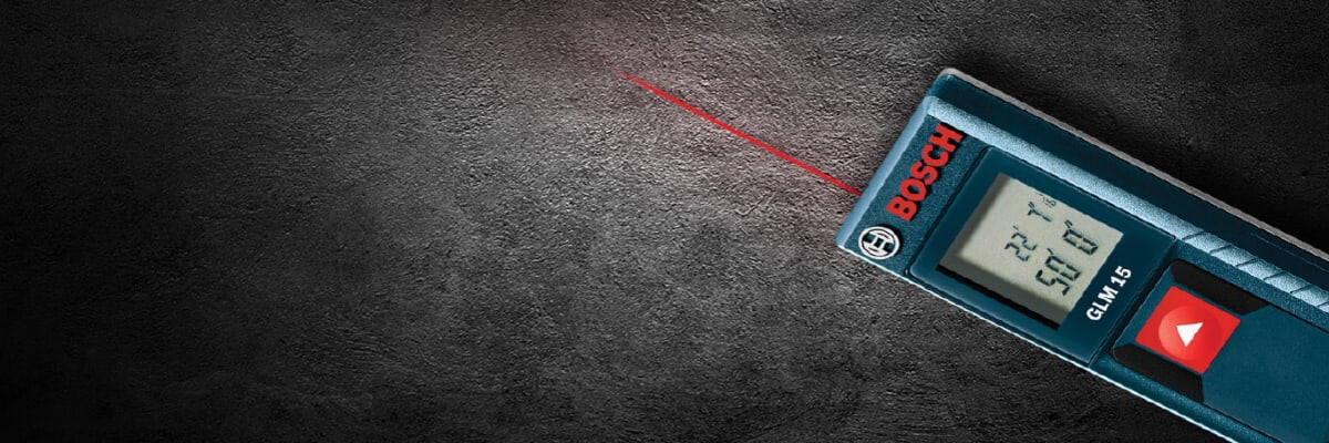 Digital Bosch measuring tool emitting a bright red laser line on a dark textured background, highlighting precise distance measurement functionality.