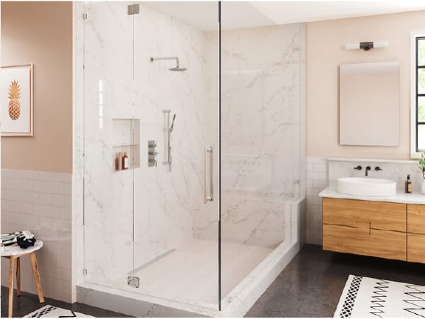Clean modern bathroom with a large glass-enclosed shower featuring marble walls, a wooden vanity with a white vessel sink, and neutral-toned decor.