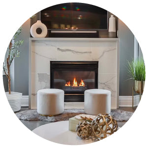 Modern living room featuring a sleek white marble fireplace with a gas fire, accompanied by two round white ottomans and decorative accents nearby.
