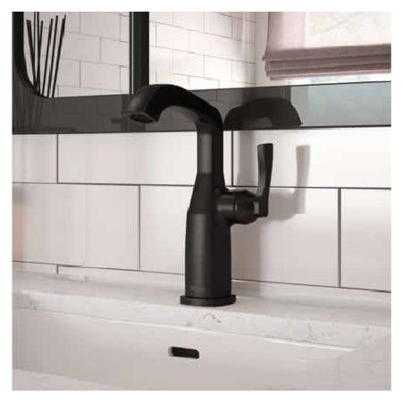 Matte black kitchen faucet with a single handle mounted on a white countertop against a subway tile backsplash with a nearby window blind.