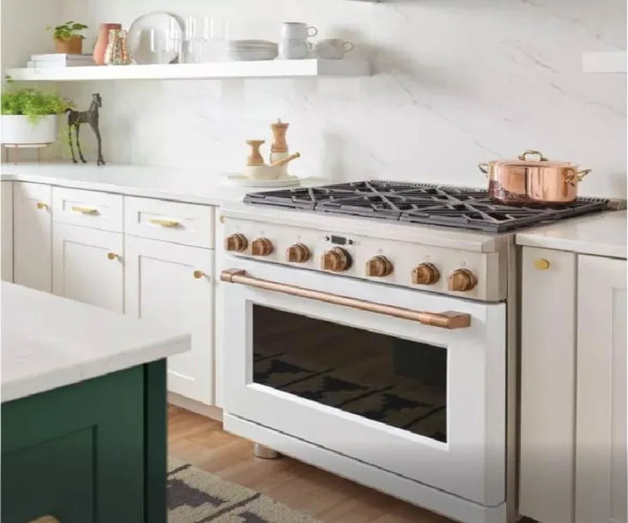 Kitchen featuring a white freestanding range with bronze knobs and handle set between white cabinetry and a marble backsplash countertop