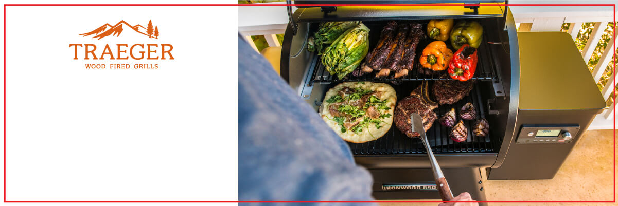 Person grilling a variety of meats and vegetables on a wood-fired grill on an outdoor patio with a digital control panel visible on the side.