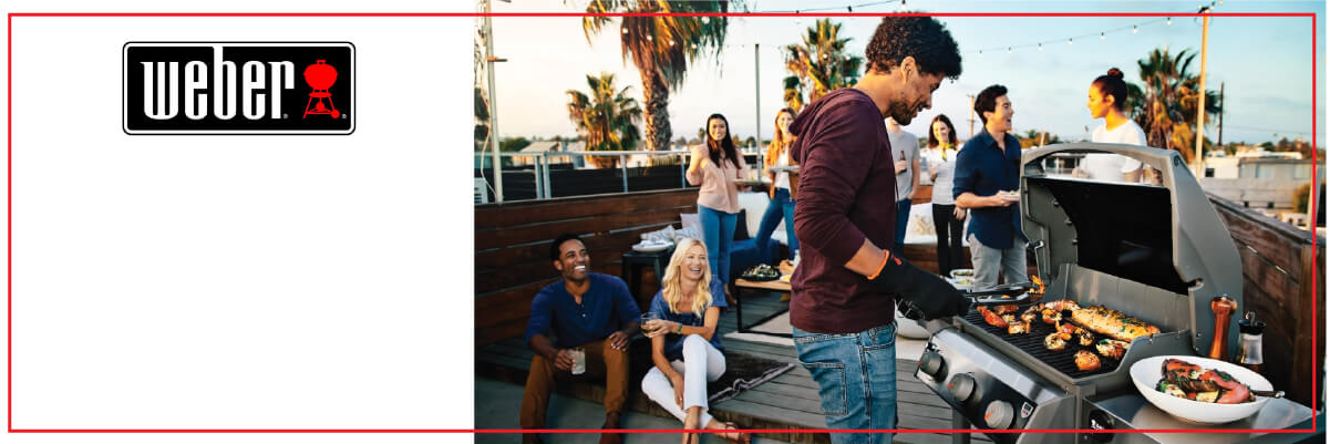 Group of friends socializing on a rooftop deck as one person grills an assortment of food on a stainless steel gas grill during sunset.