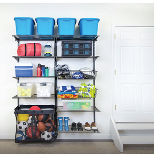 Wall-mounted black wire shelving system holding blue storage bins, sports equipment, water bottles, helmets, and outdoor gear next to a white door.