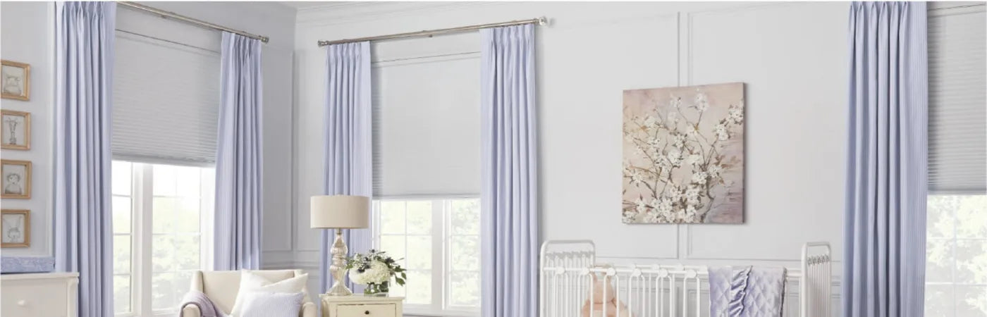 Bright and airy nursery room featuring soft pastel curtains, white crib, beige armchair, and floral wall art above the crib.
