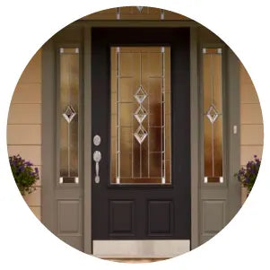 Front entryway featuring a dark-colored exterior door with decorative glass panels and matching sidelights framed by neutral-toned siding and accented by potted plants.